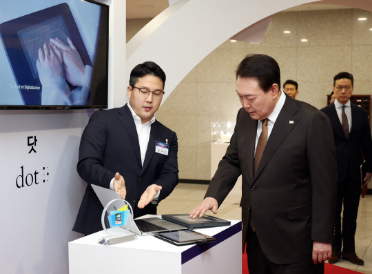 윤석열 대통령이 2일 서울 용산 대통령실 청사에서 열린 국제전자제품박람회(CES) 디지털 기술혁신 기업인과의 오찬 간담회에 앞서 2023 CES 접근성(Accessibility) 부문에서 최고 혁신상을 수상한 시각장애인용 디바이스와 소프트웨어 개발사 소셜벤처 닷 부스를 방문, 시각장애인을 위한 촉각 패드를 살펴보고 있다. 연합뉴스